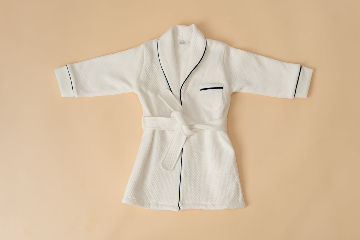 White quilted Pima cotton kids bathrobe with navy piping by Pipa & Pierre